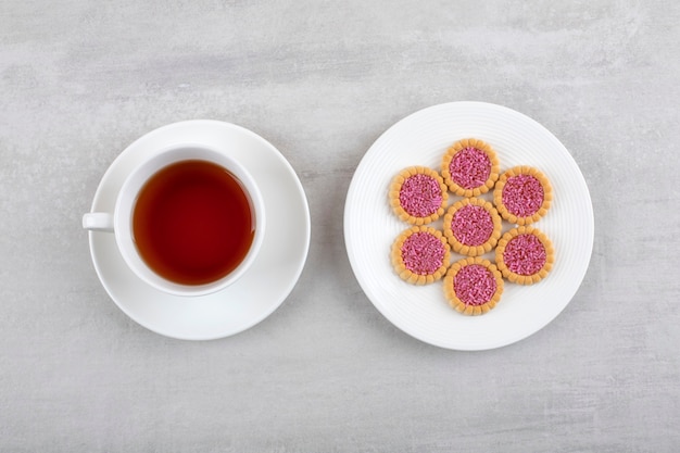 Photo gratuite une tasse blanche de thé chaud et des biscuits avec des pépites sur une assiette blanche.