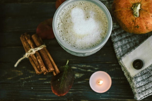 Tasse bleue avec latte de citrouille épicée sur une planche de bois avec un pull