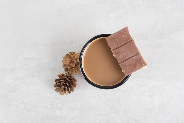 Tasse de café aux pommes de pin et barre de chocolat