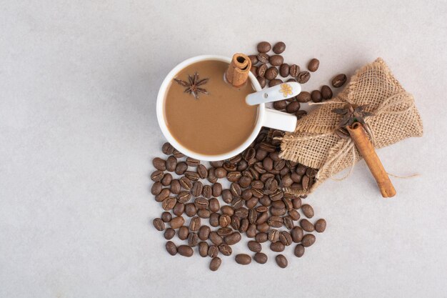 Une tasse de café avec des bâtons de cannelle et des grains de café sur fond de marbre. photo de haute qualité