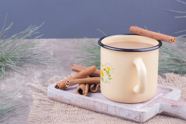 Une tasse de café avec des bâtons de cannelle sur une planche de bois rustique.