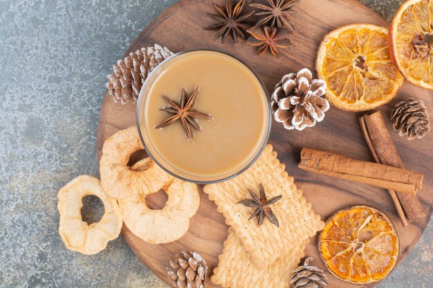 Tasse de café avec des bâtons de cannelle et des pommes de pin sur une plaque en bois. Photo de haute qualité