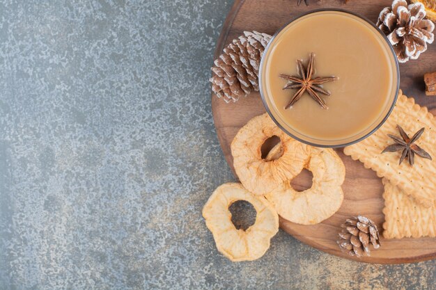 Tasse de café avec des bâtons de cannelle et des pommes de pin sur une plaque en bois. Photo de haute qualité