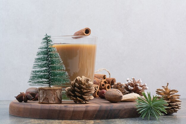 Tasse de café avec des bâtons de cannelle et des pommes de pin sur une plaque en bois. Photo de haute qualité