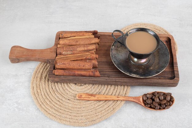 Tasse de café avec des bâtons de cannelle sur tableau noir et grains de café