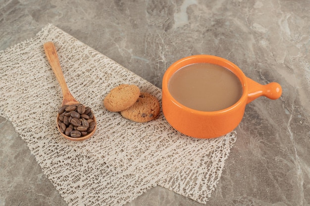 Tasse de café, biscuits sur une surface en marbre avec des grains de café