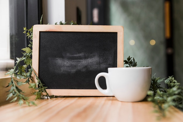 Tasse à café blanche avec ardoise noire sur la surface en bois