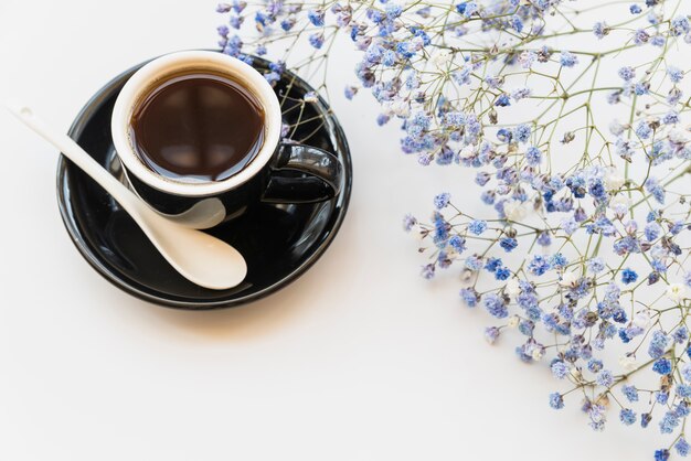 Photo gratuite tasse de café et de branches de fleurs bleues