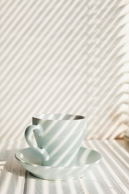 Tasse à café en céramique blanche avec soucoupe près de la table en bois