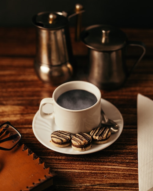 Tasse de café chaud avec des biscuits sur la table sous les lumières