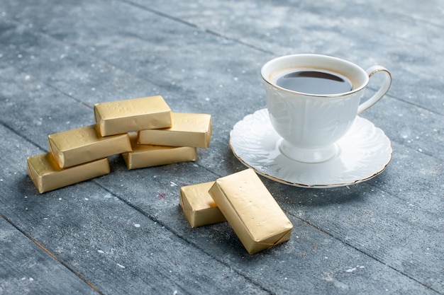 Tasse de café chaud et fort avec du chocolat en forme d'or sur bleu, boisson au cacao café chaud