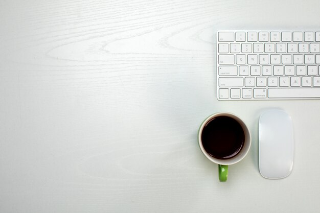 Une tasse de café et un clavier et une souris sans fil