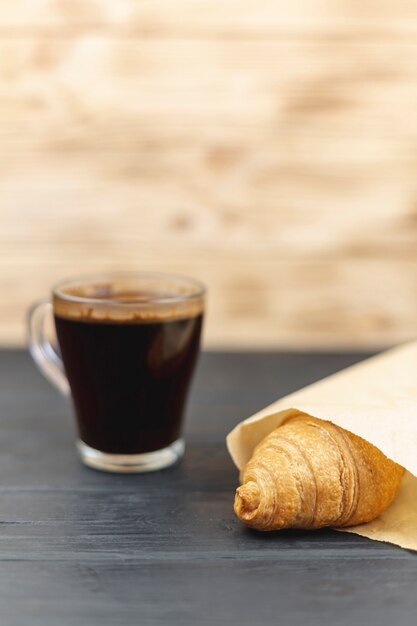 Tasse à café avec un croissant sur une table noire