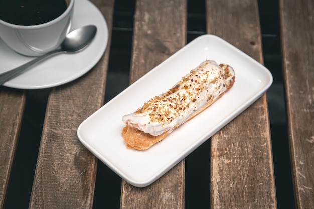 Photo gratuite tasse de café et éclair sur une table en bois libre