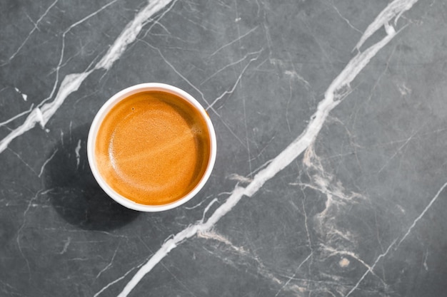 Tasse de café expresso chaud dans une tasse de papier à emporter sur une table en pierre dans un fond de café monotone avec copie espace pause café