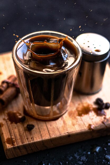 Tasse à café expresso double avec des bâtons de cannelle et des grains de café sur une planche de bois
