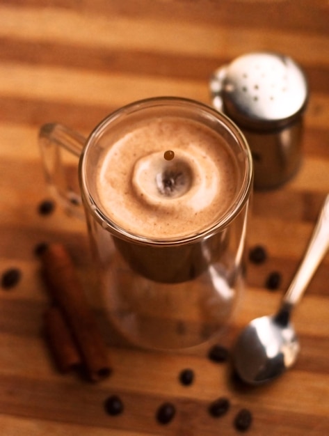 Tasse à café expresso double avec des bâtons de cannelle et des grains de café sur une table en bois