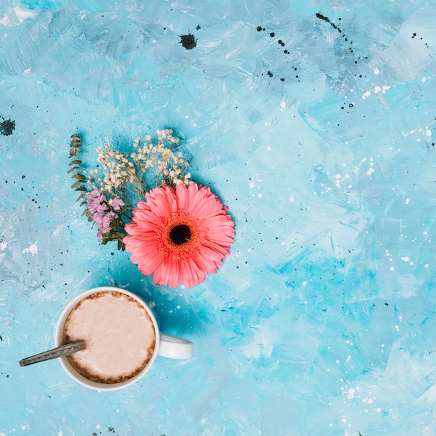 Photo gratuite tasse à café avec des fleurs sur la table bleue