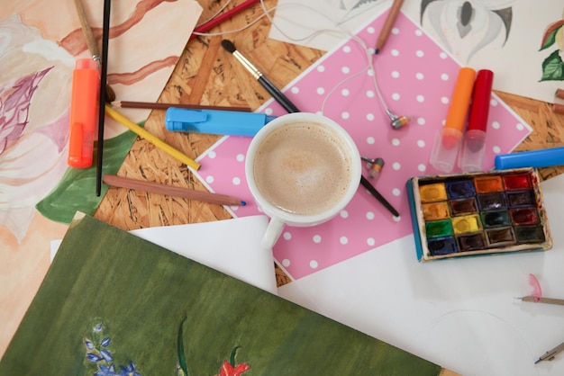 Photo gratuite tasse de café et fournitures de peintres sur table