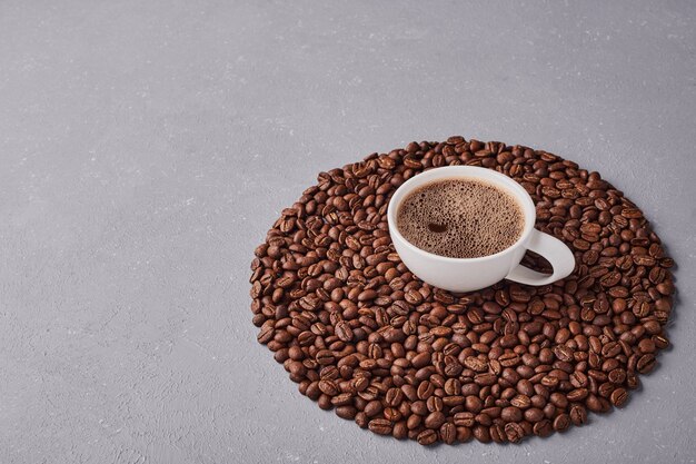 Une tasse de café sur des grains d'arabica.