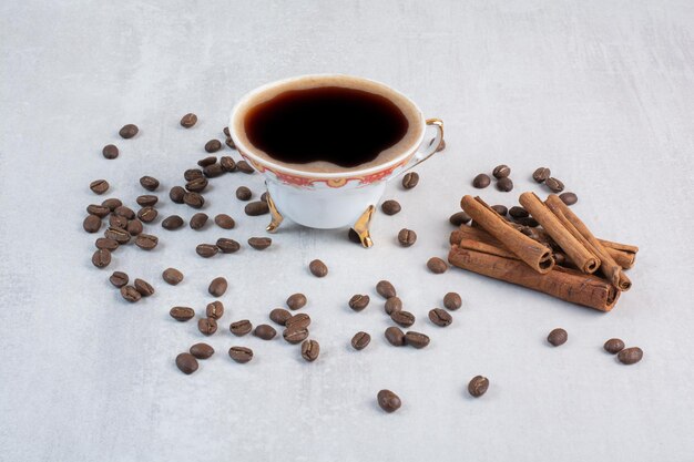 Tasse de café avec des grains de café et des bâtons de cannelle