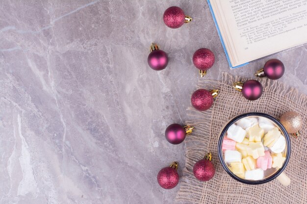 Une tasse de café avec des guimauves et des boules de Noël.