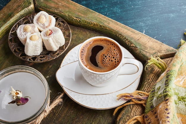 Une tasse de café avec de la mousse dans une soucoupe blanche servie avec du lokum.