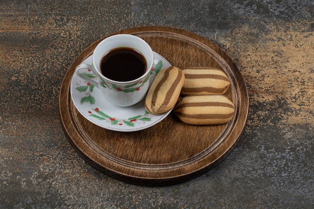 Tasse de café noir avec des biscuits sur une surface en marbre.