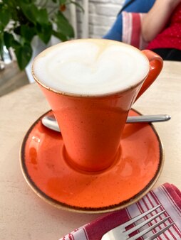 Tasse à café orange avec café au lait aromatique sur une table rustique, petit-déjeuner confortable dans un café. style vintage