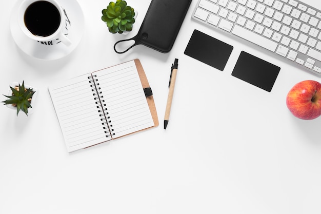 Tasse à café; plante de cactus; carte; Pomme; agenda et stylo sur fond blanc