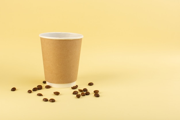 Une tasse de café en plastique vue de face avec des graines de café brun sur le mur jaune