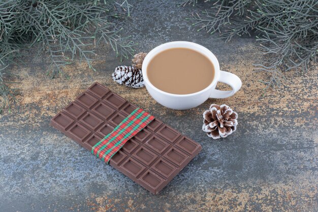 Une tasse de café avec des pommes de pin et du chocolat. photo de haute qualité