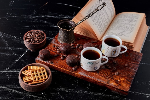 Une tasse de café avec des pralines au chocolat et des biscuits.