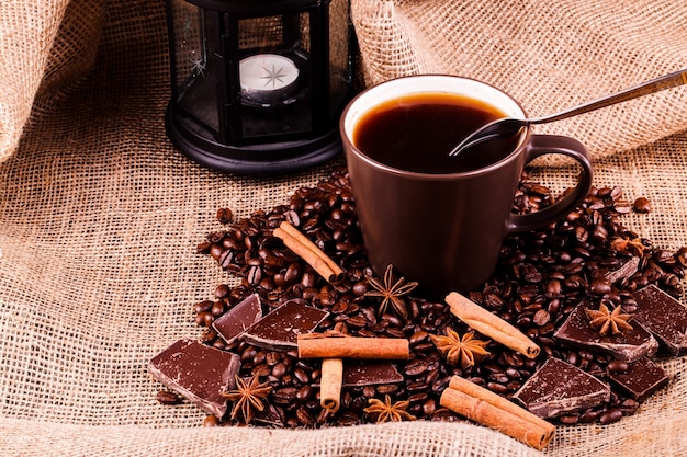 Tasse de café se dresse sur les grains de café et le chocolat