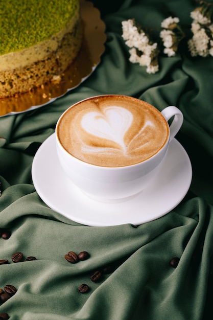 tasse de cappuccino avec grains de café et gâteau sur la table