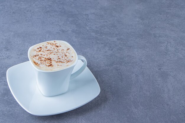 Une tasse de cappuccino sur une soucoupe , sur le fond bleu.