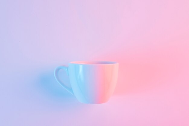 Une tasse en céramique blanche vide sur fond rose