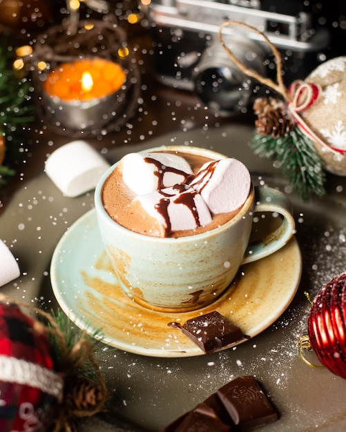 Une tasse de chocolat chaud avec des guimauves et du sirop de chocolat