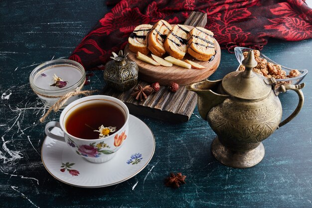 Une tasse décorative de tisane avec des tranches de rollcake.