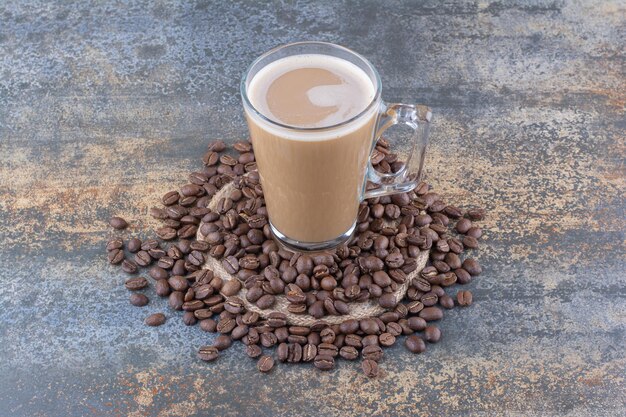 Une tasse de délicieux café avec des grains de café sur du marbre