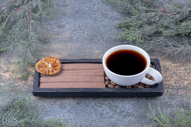Tasse d'espresso, biscuits et grains de café sur plaque noire.