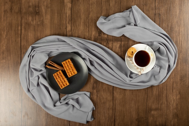 Une tasse d'espresso et de gaufres dans une soucoupe noire. vue de dessus