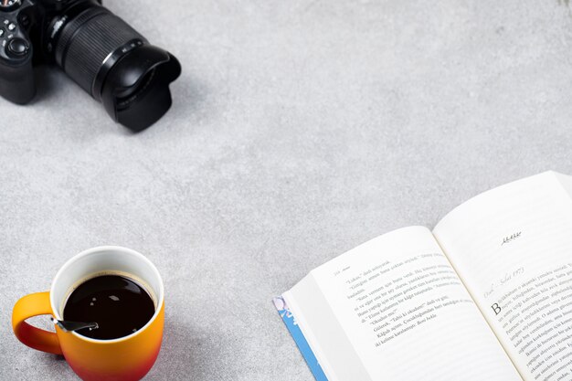 Une tasse d'espresso avec un livre et un appareil photo sur la table