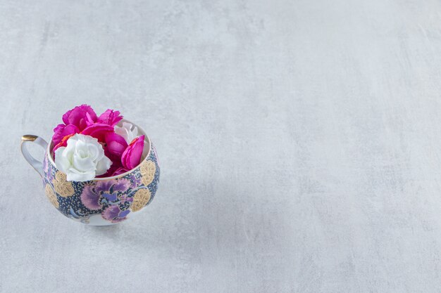 Une tasse de fleurs violettes et blanches, sur le tableau blanc.