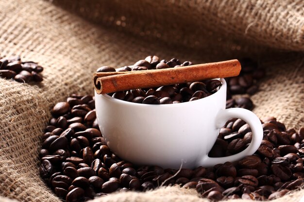 Photo gratuite tasse avec grains de café et bâton de cannelle