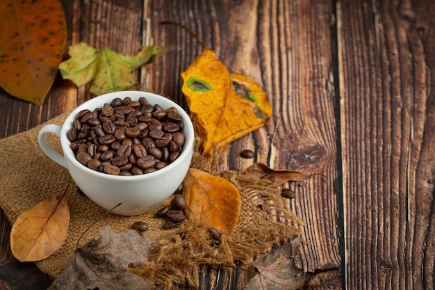 Tasse de grains de café et de feuilles sèches sur plancher en bois, bonjour concept de septembre.