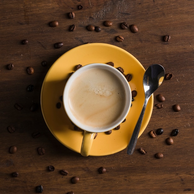 Tasse jaune avec boisson près de grains de café