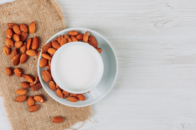 Une tasse de lait sur du bois blanc et un morceau de fond de sac, vue de dessus. espace libre pour votre texte