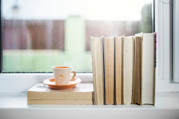 Tasse et livres sur le rebord de la fenêtre