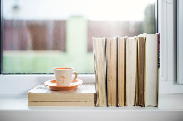 Tasse et livres sur le rebord de la fenêtre